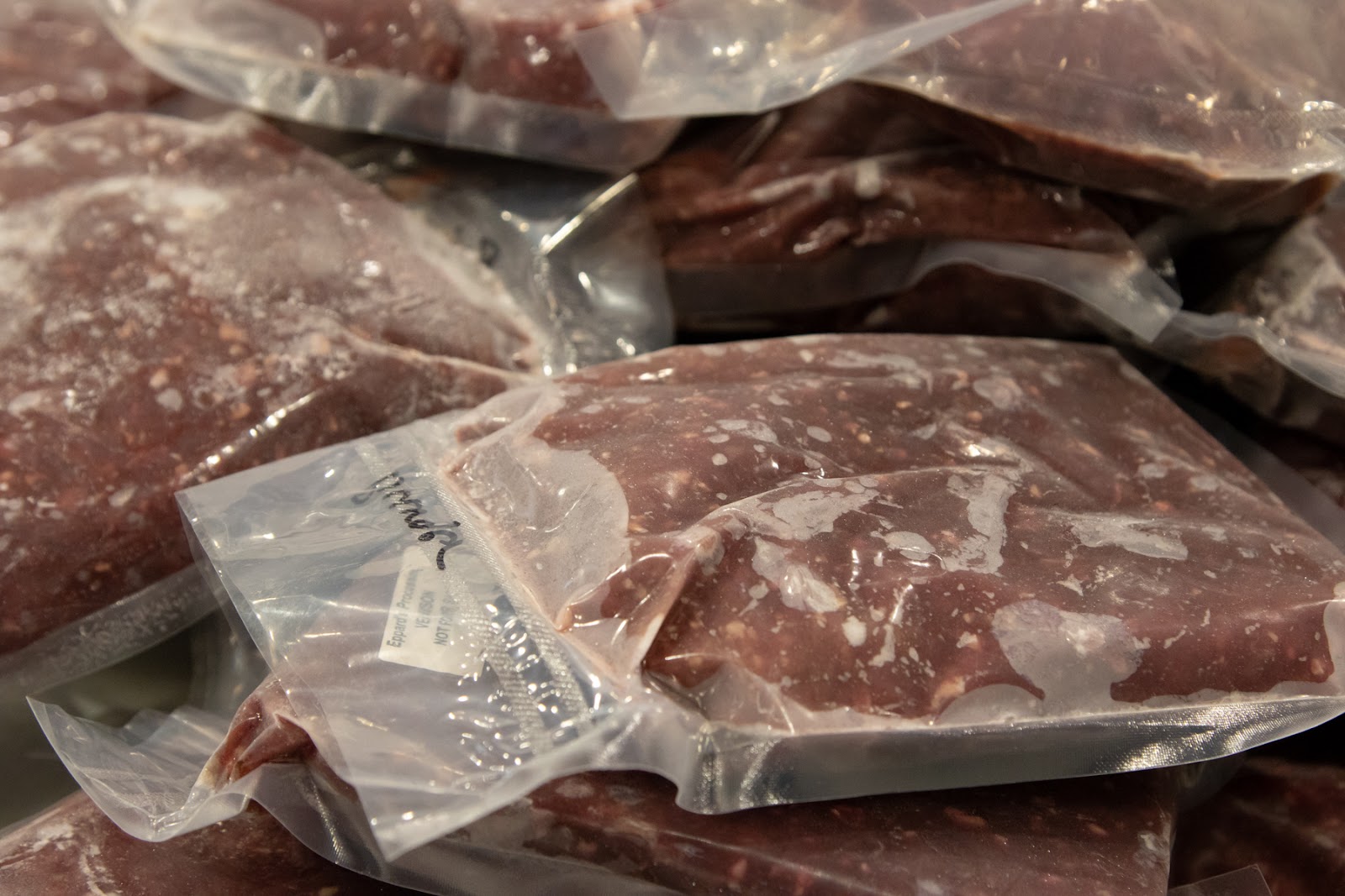 A closeup shows packages of frozen red meat.