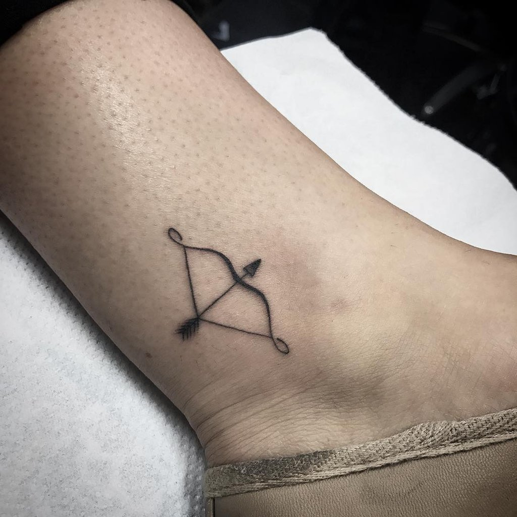 Minimal bow and arrow tattoo on ankle