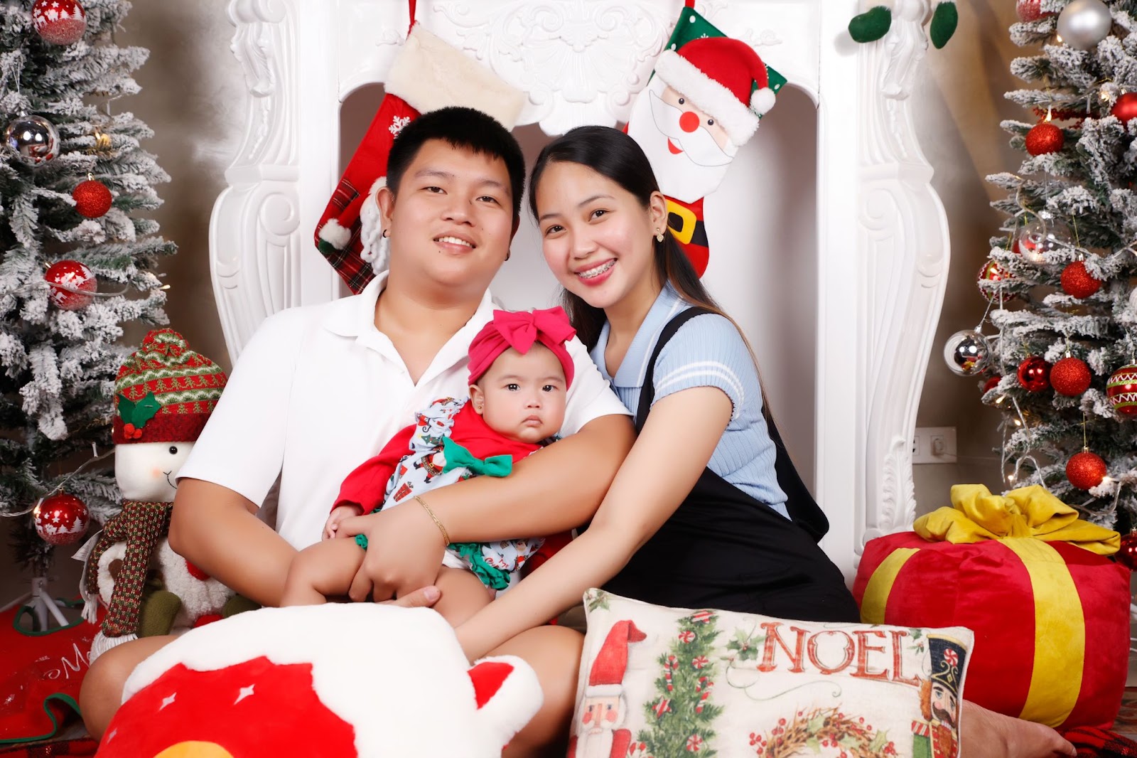 newborn christmas photo idea: newborn dressed in a cute Christmas dress posing with parents
