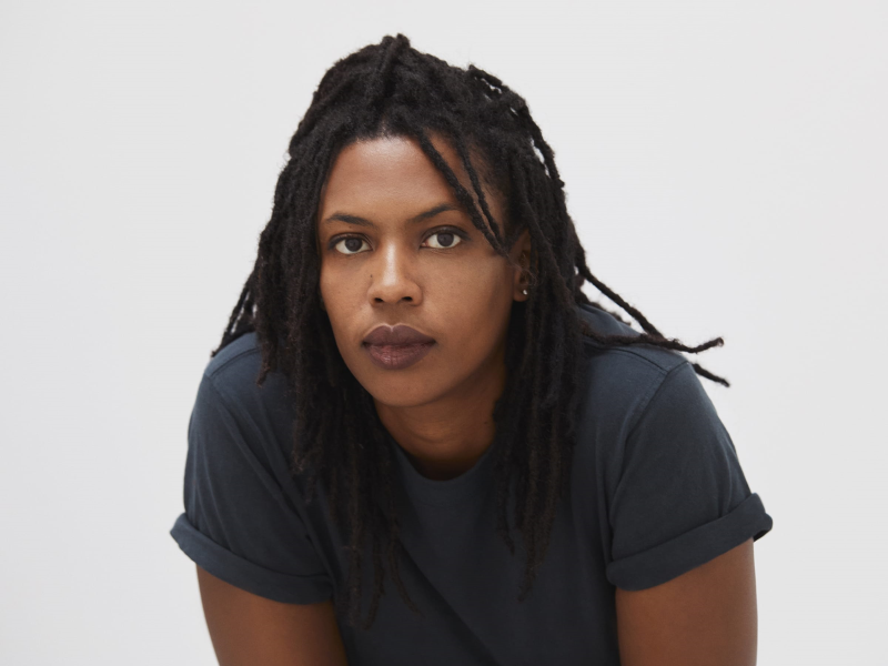 A person with dreadlocks looking at the camera

Description automatically generated