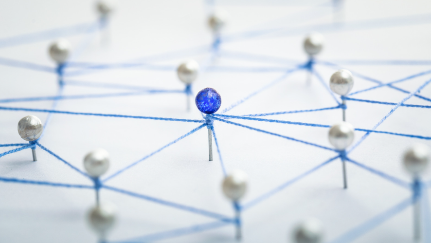A blue push pin surrounded by white push pins, all of which are interconnected to each other.