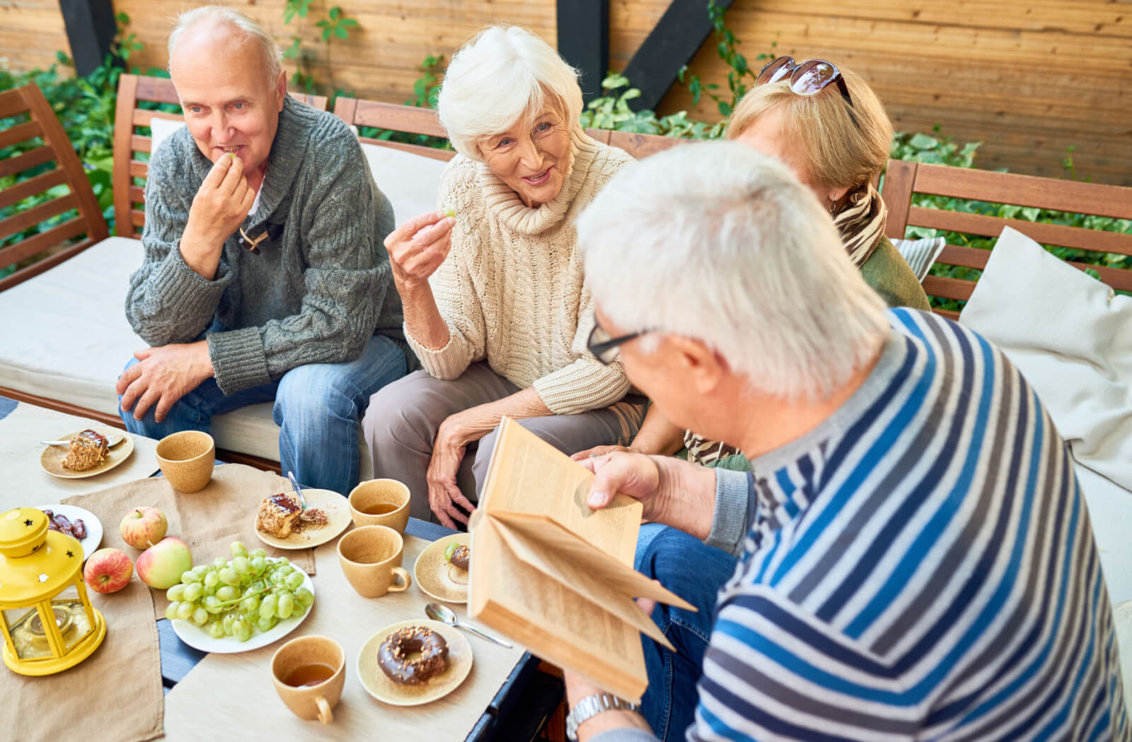 A group of older adults hanging out outdoors while having some snacks together.