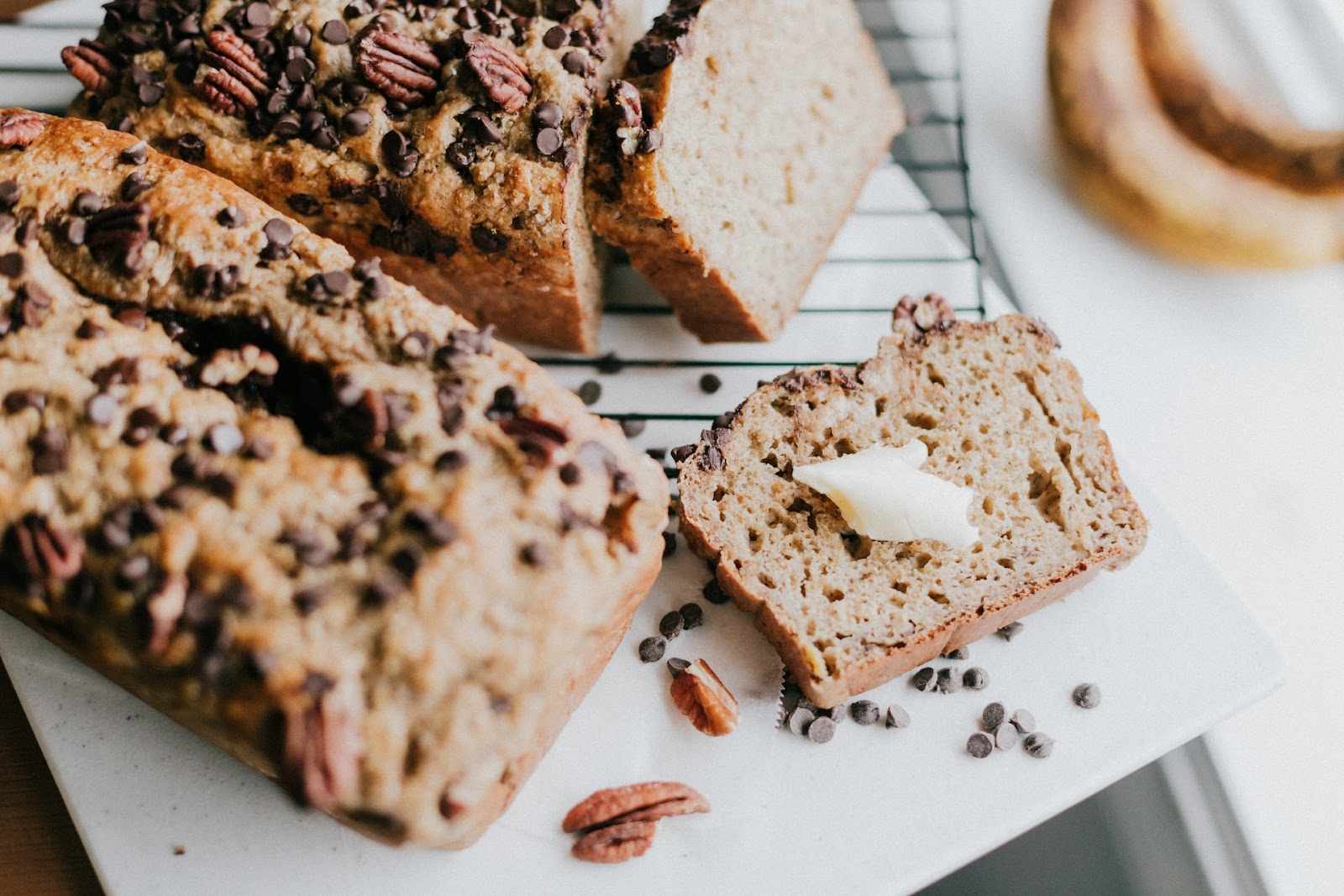 Banana bread with nuts and chocolate chip and butter on a baking rack