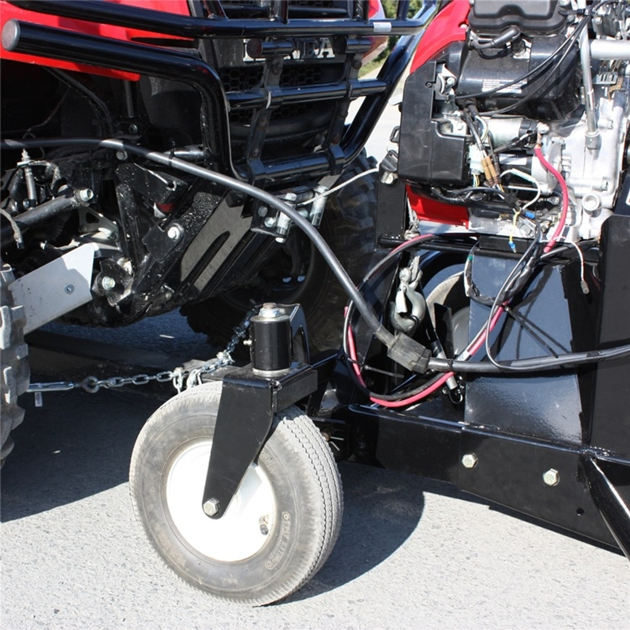 A front-oblique, closeup image of a Bercomac John Deere Gator XUV Snowblower, installed on a UTV, showing the wheel, motor, and other systems.
