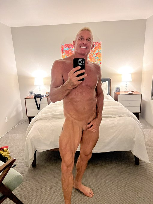 Matthew Figata smiling naked while taking an iphone mirror selfie holding his cock