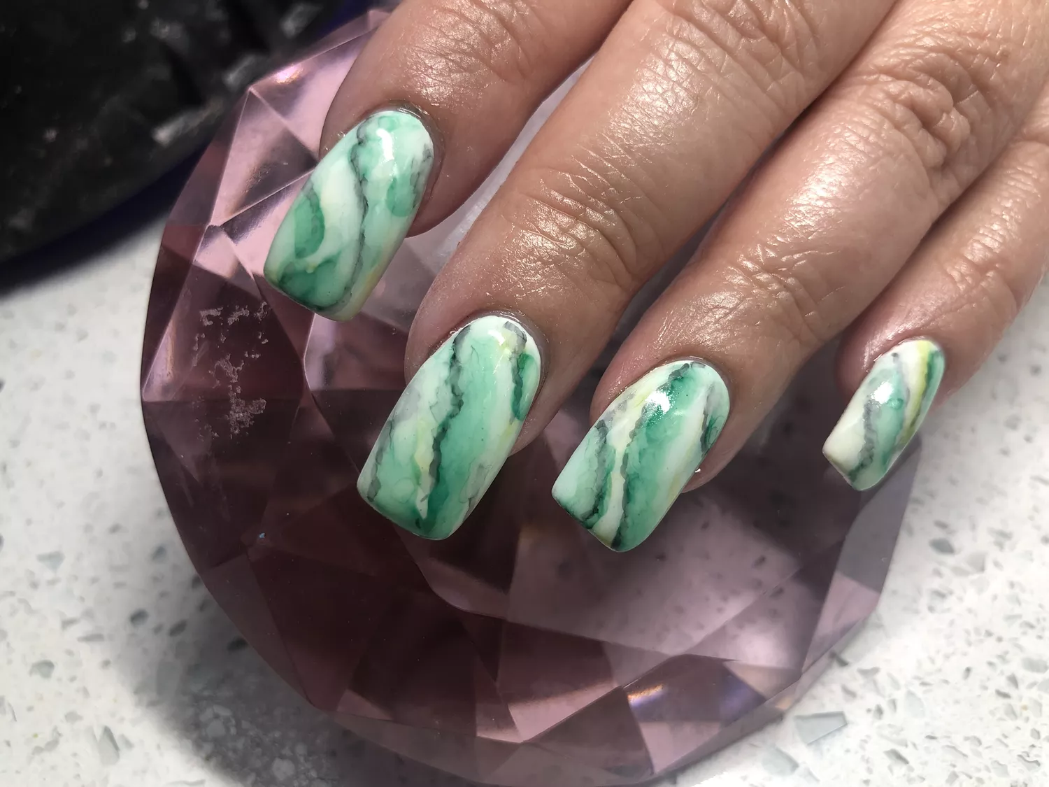 Close up view of a green nail design 