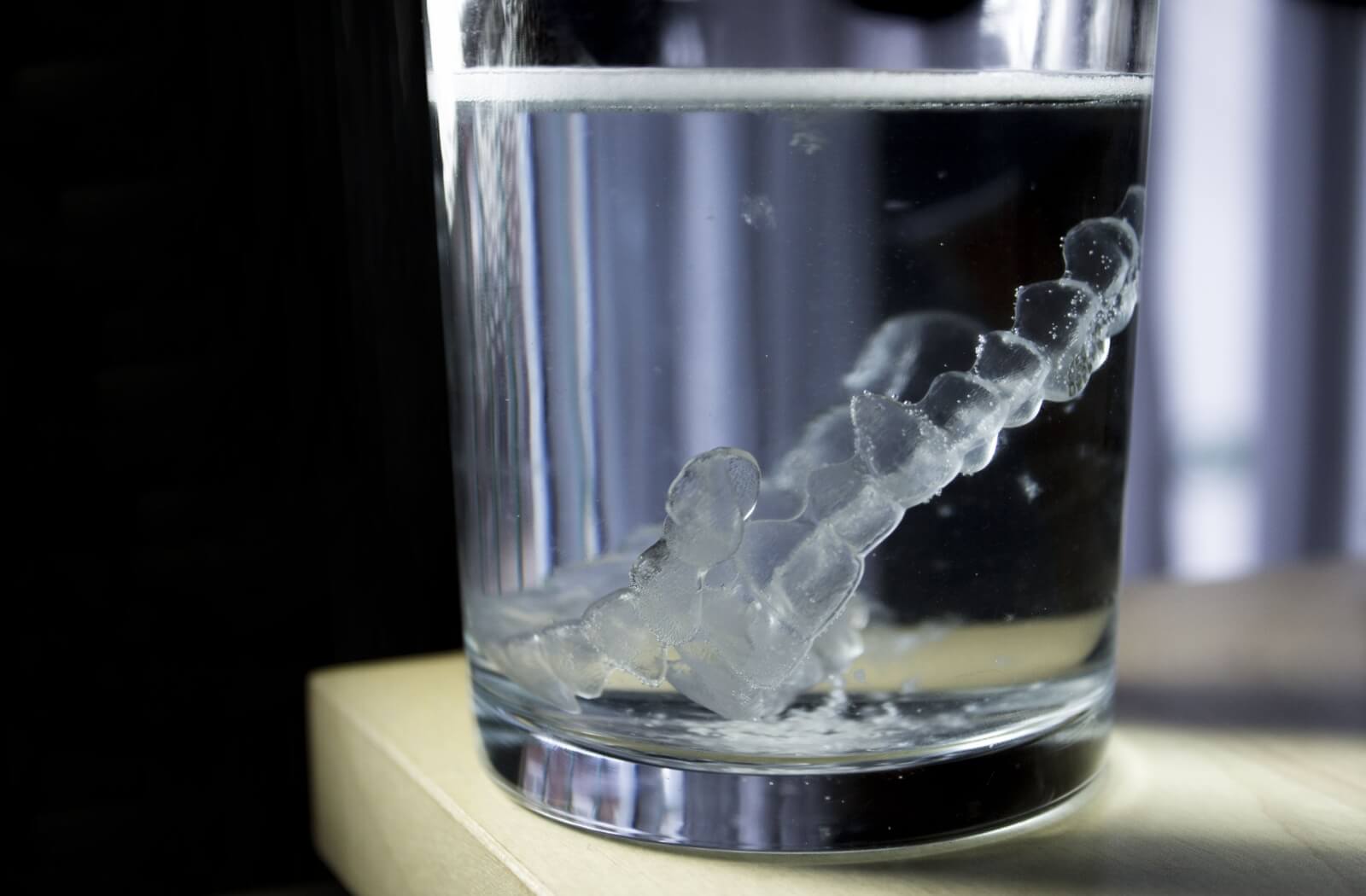 A pair of Invisalign aligners soaked in lukewarm water.
