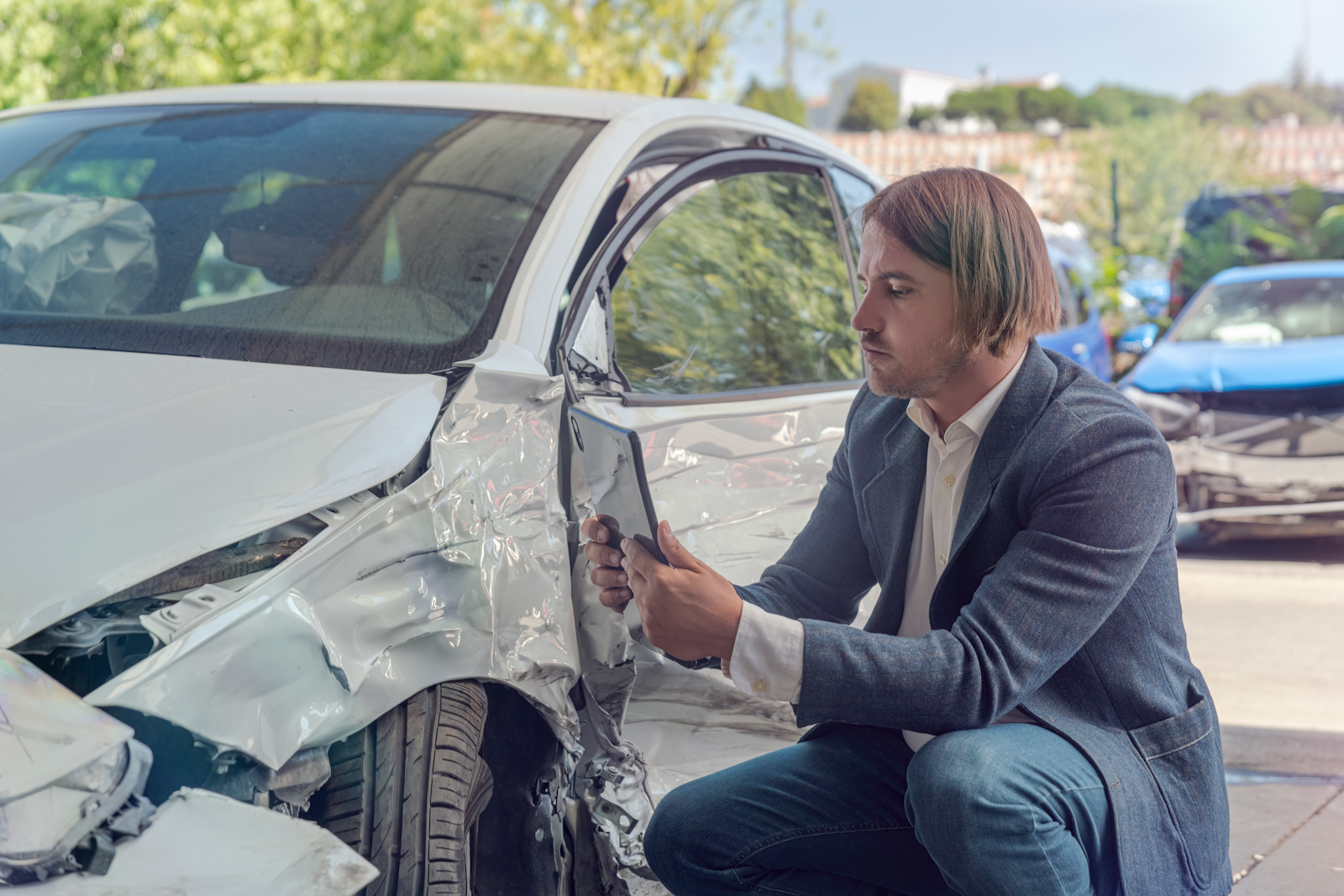 car accident claims adjuster taking a picture of the damage