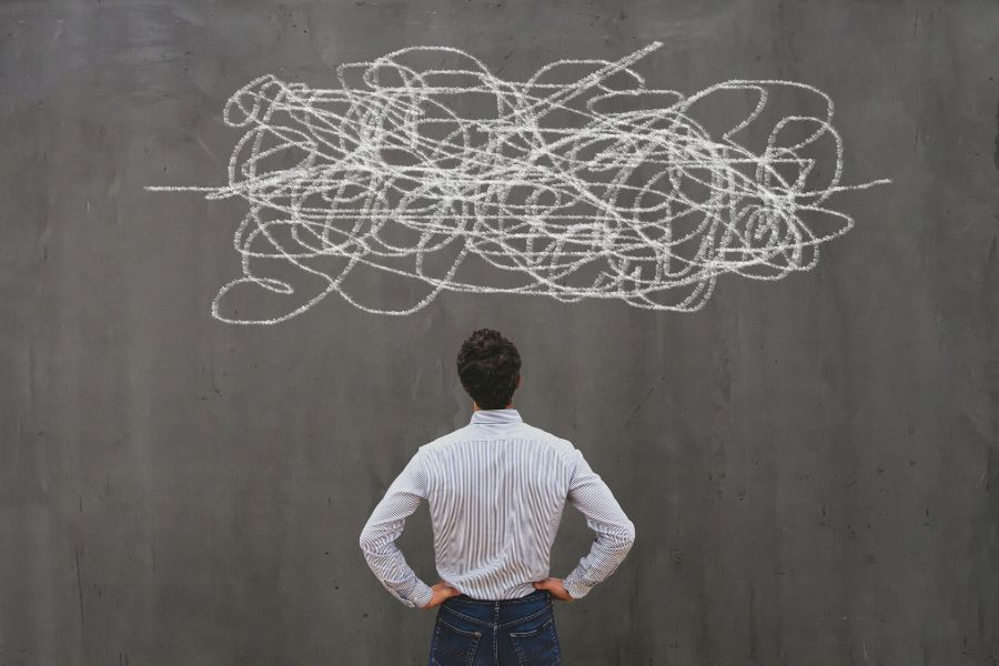 Person in front of a chalkboard with scribbled lines.