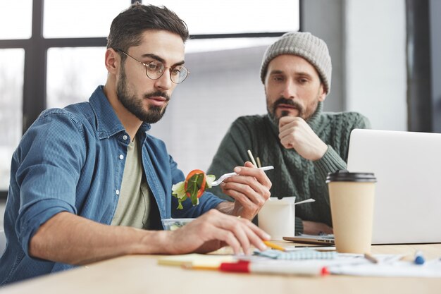 Male coworkers in office with lunch