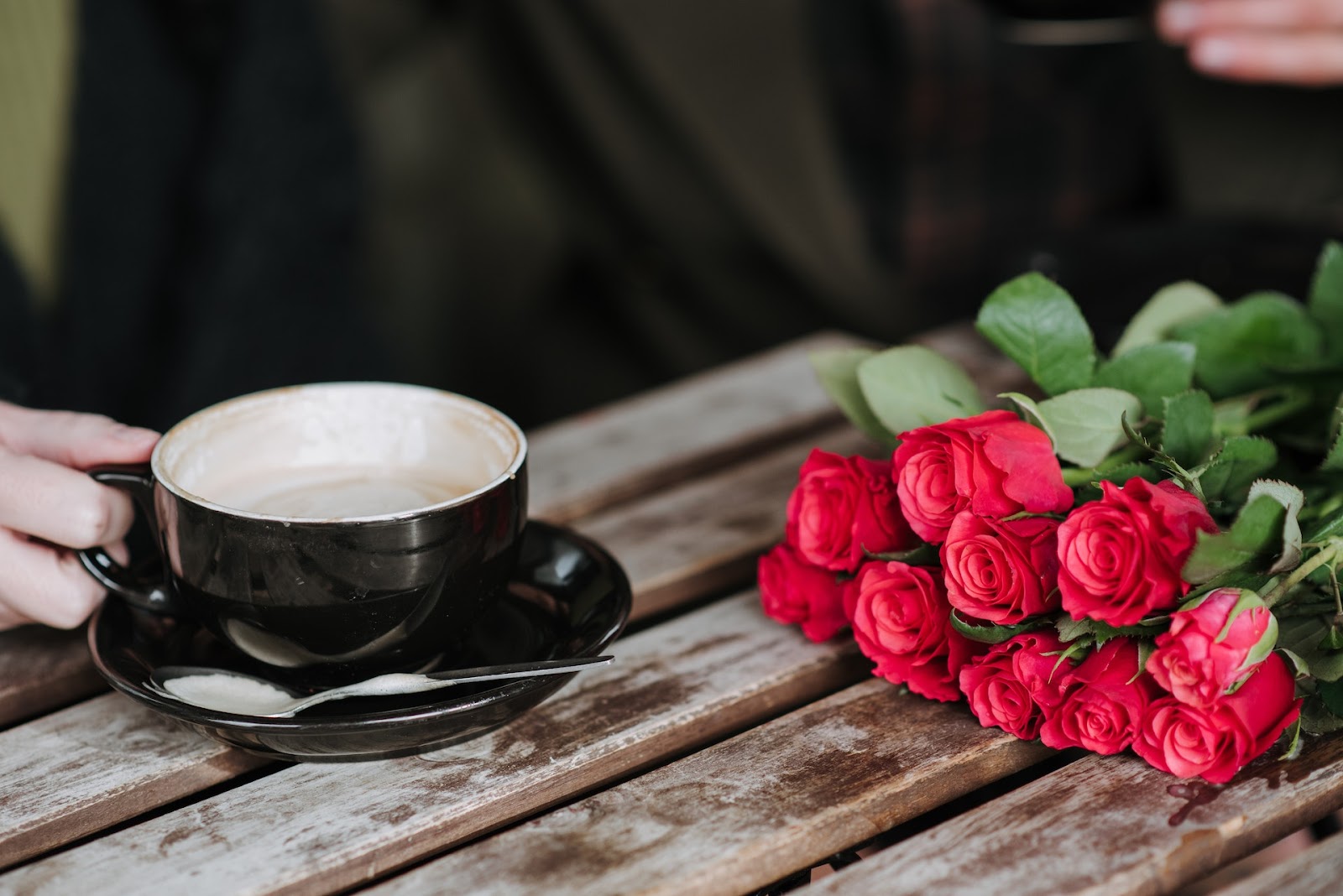 Xícara de café e buquê de flores em uma mesa de madeira demonstrando o romantismo em francês