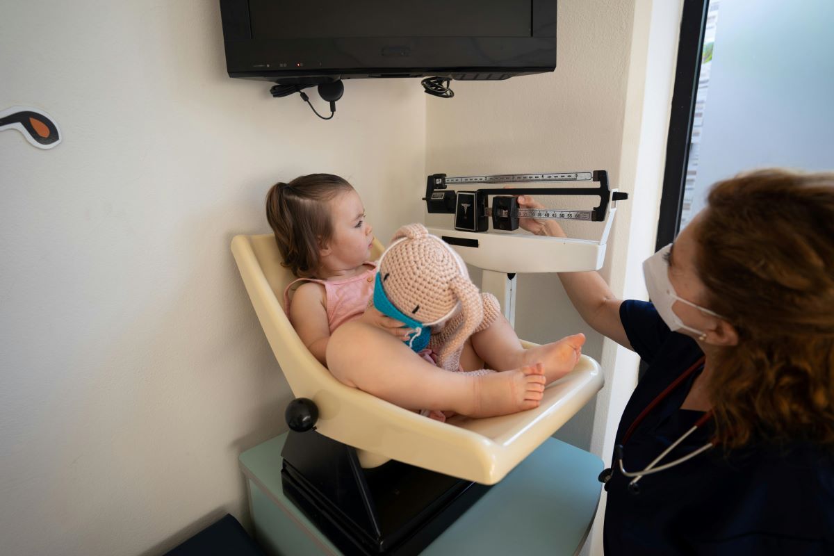 a health worker weighing a little girl