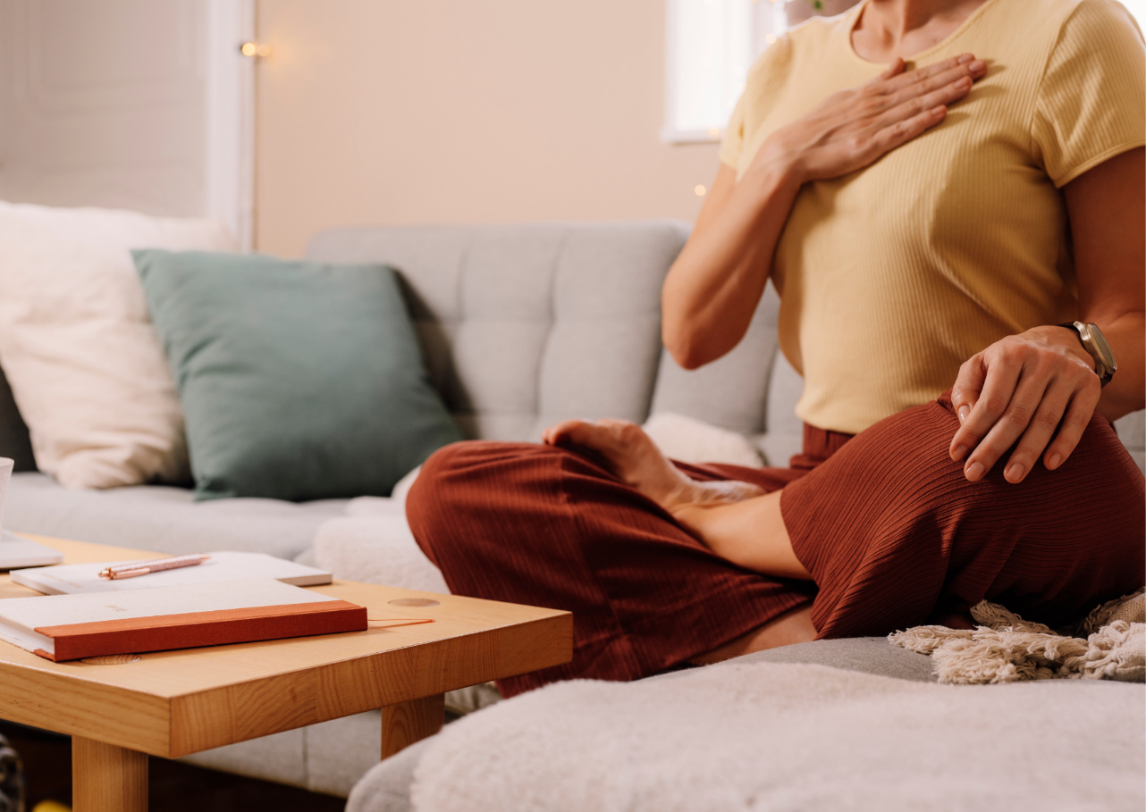 A person sitting on a couch with her hands on her chest

Description automatically generated