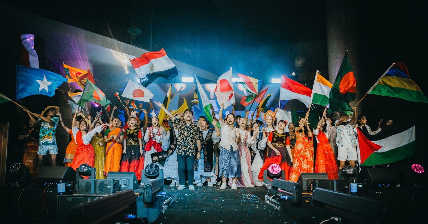A group of people on a stage with flags

Description automatically generated