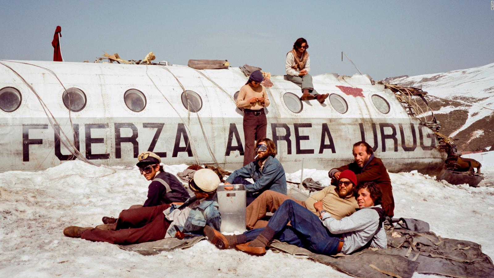 Sobrevivientes del accidente aéreo en Los Andes, sentados en la nieve y encima del avión, en La Sociedad de la nieve