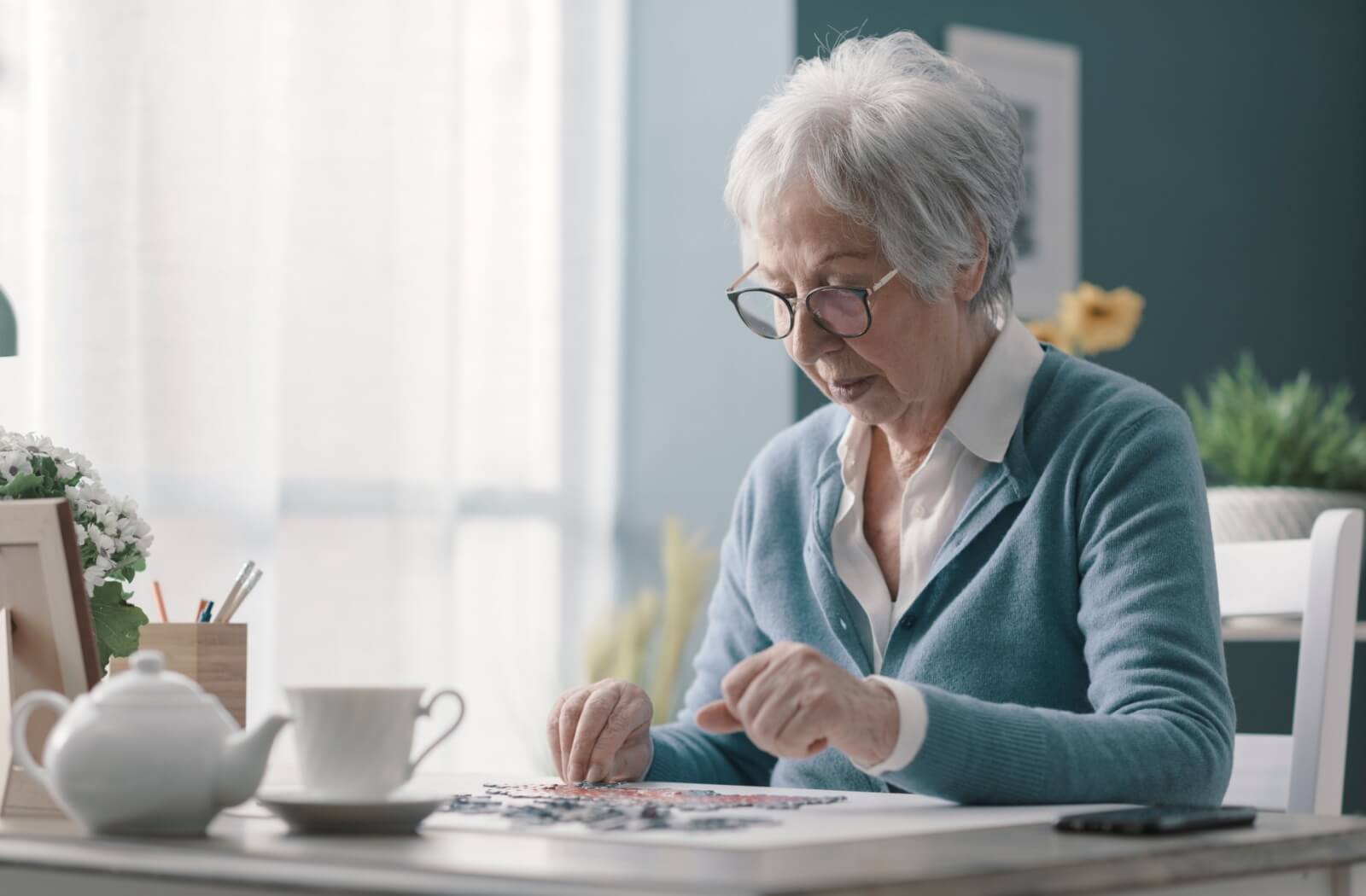 An older adult woman solving a jigsaw puzzle to improve her memory.