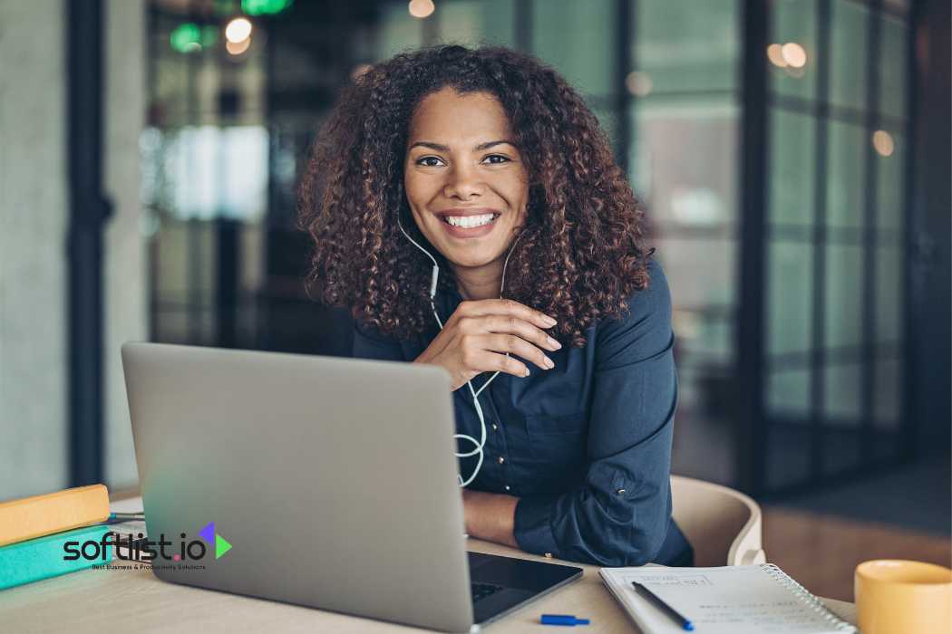 Smiling woman with curly hair working on a laptop
