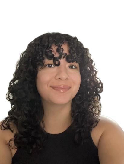 A person with curly hair smilingDescription automatically generated