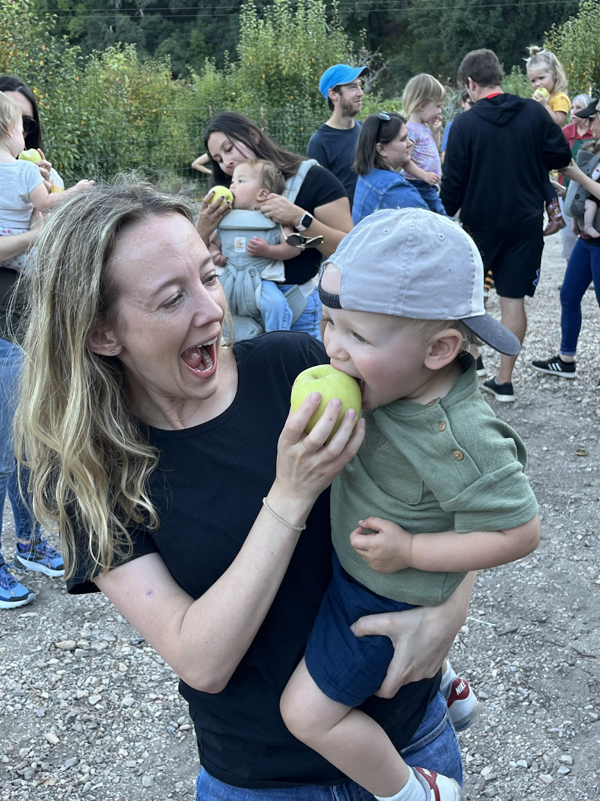 mom holding son who is taking a bite of an apple