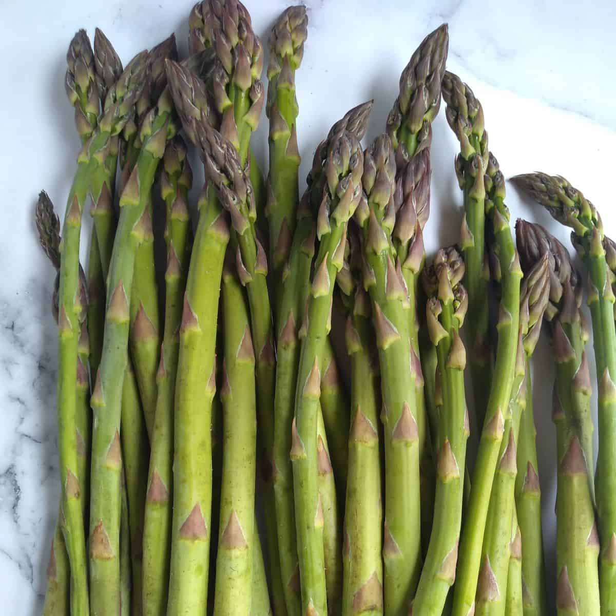 A bunch of asparagus on a marble surface

Description automatically generated