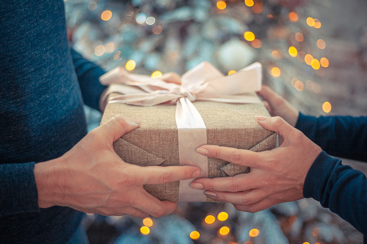 a person exchanging a beige gift with a pink bow to another person