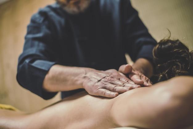 Man massaging a woman oiled hands on a body relaxing the muscles health well-being wellness concept