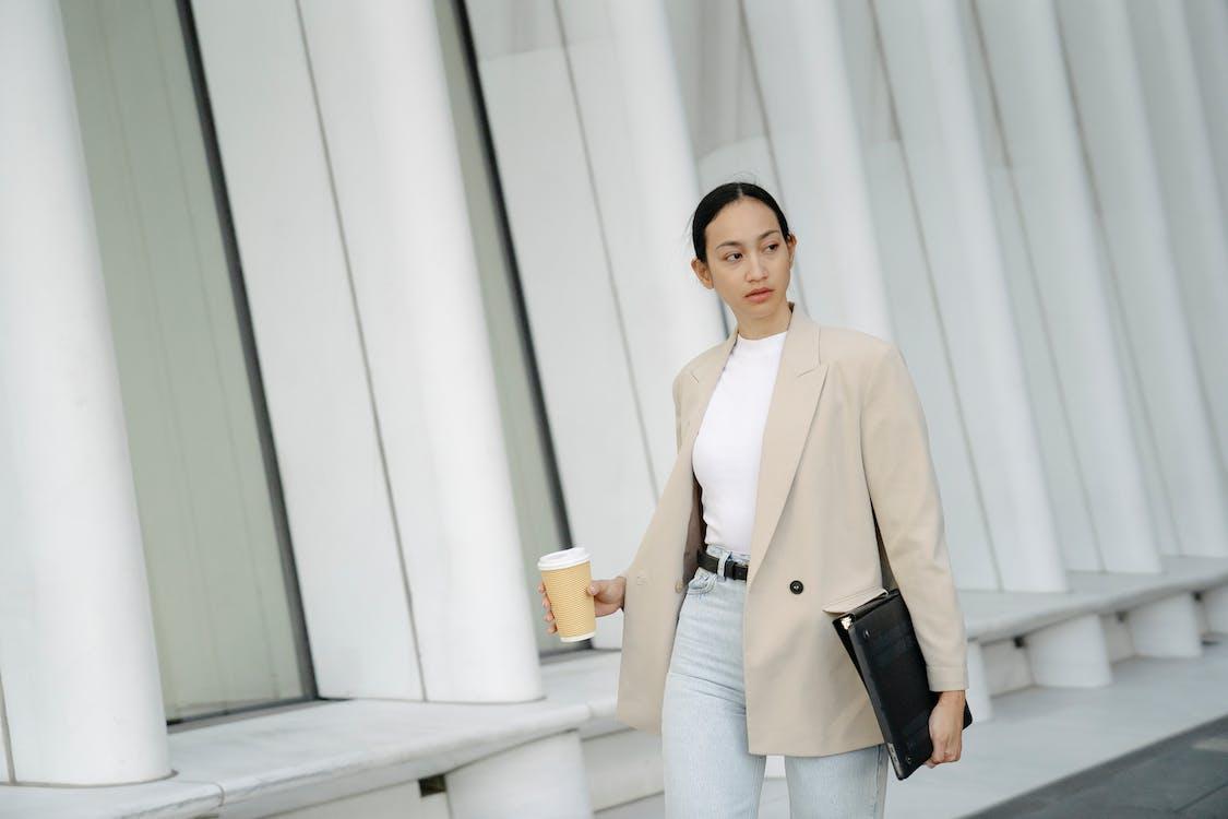 Free Serious ethnic woman with takeaway coffee and folder Stock Photo