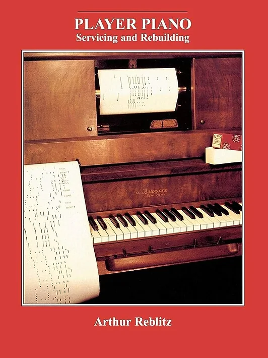 Image: [Fig.5.] The cover of "Player Piano: Servicing and Rebuilding" by Arthur Reblitz. A red frame with the title and author's name at the top and bottom respectively. In the center is a photo of a player piano, in which is embedded a sheet of paper with holes of varying lengths running up and down it. Photo courtesy of the National Museum of American History.