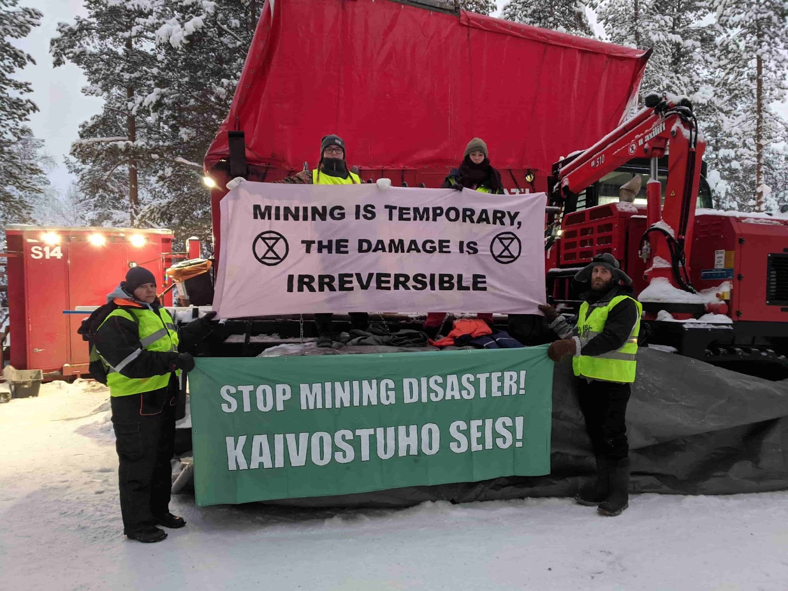 Rebels stand on drill machinery holding anti-mining banners