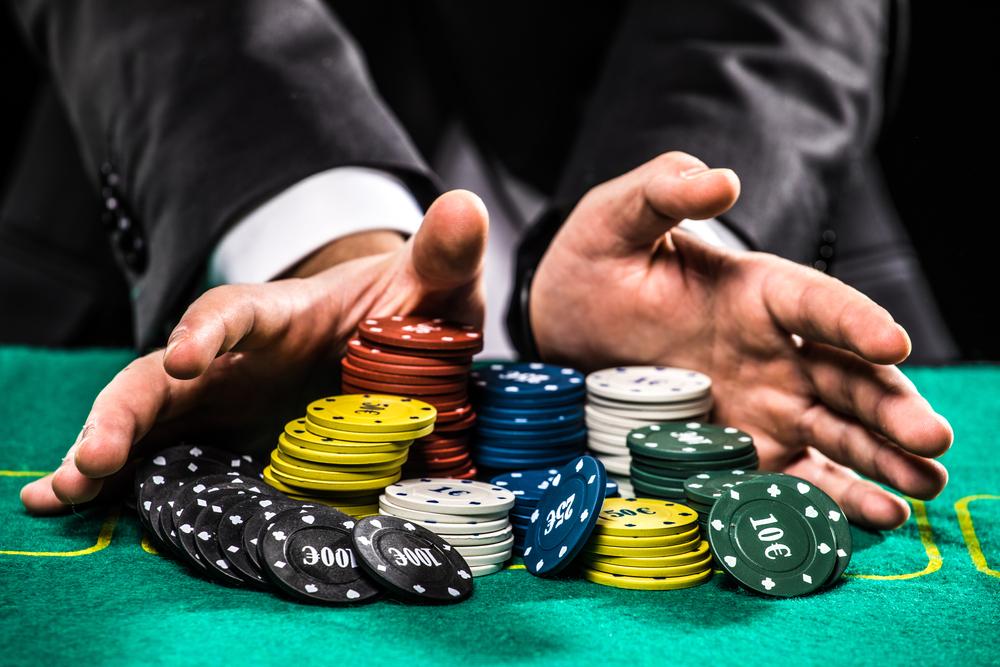 A person's hands over a pile of poker chips

Description automatically generated