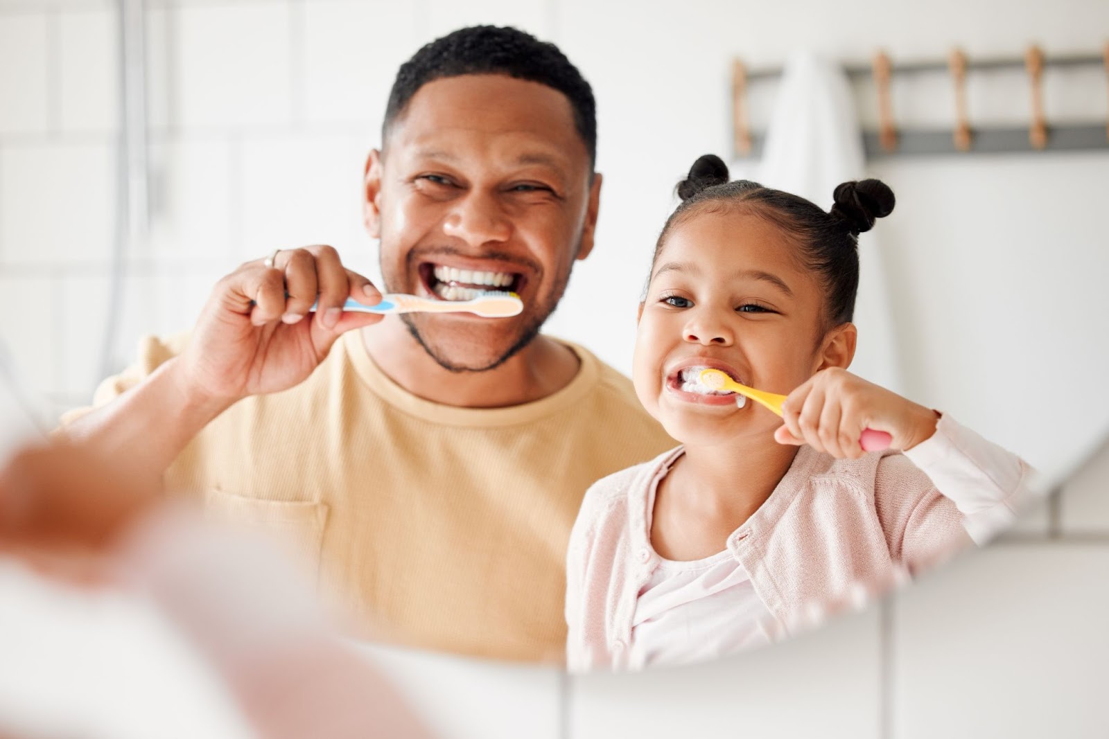 A man and his daughter brushing their teeth together.
