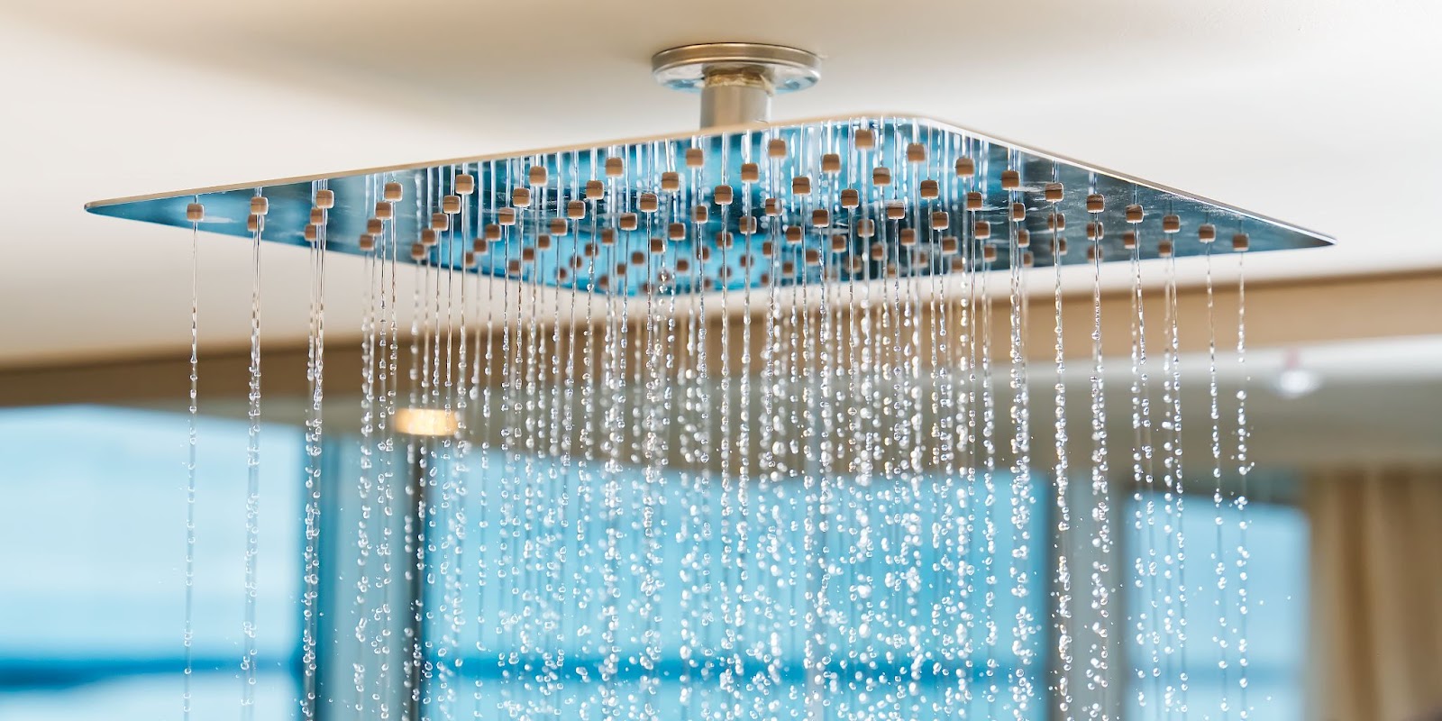 Water cascades from a chrome rain shower head, showcasing a modern design.