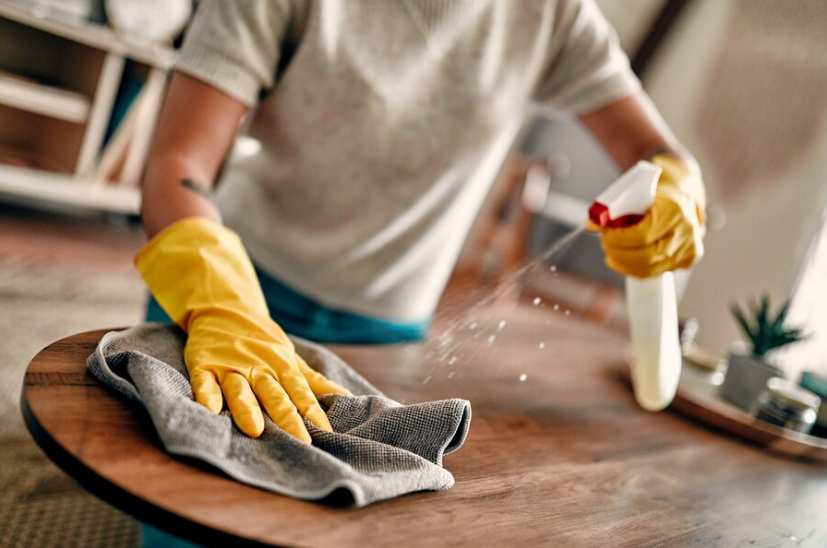 Person cleaning a wooden table