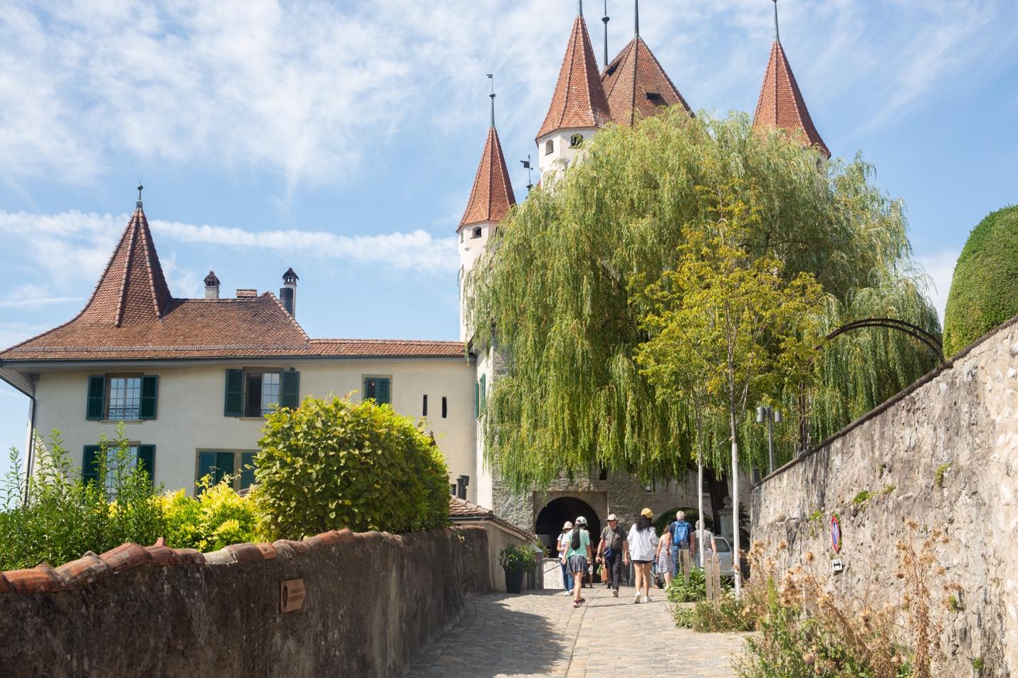 A group of people walking down a path with a castle

Description automatically generated