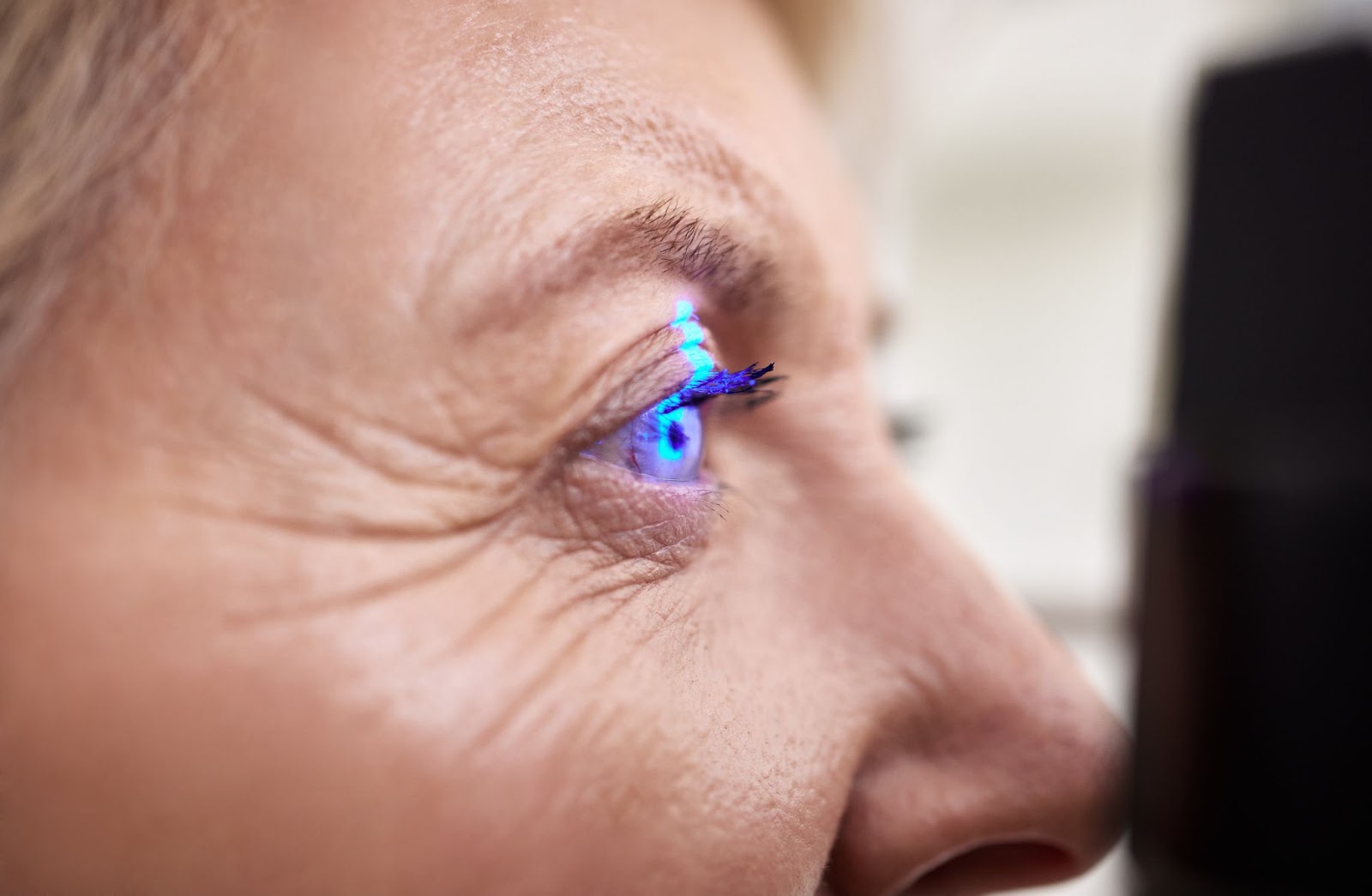 A woman looking at an eye testing machine that shines a light on her eye
