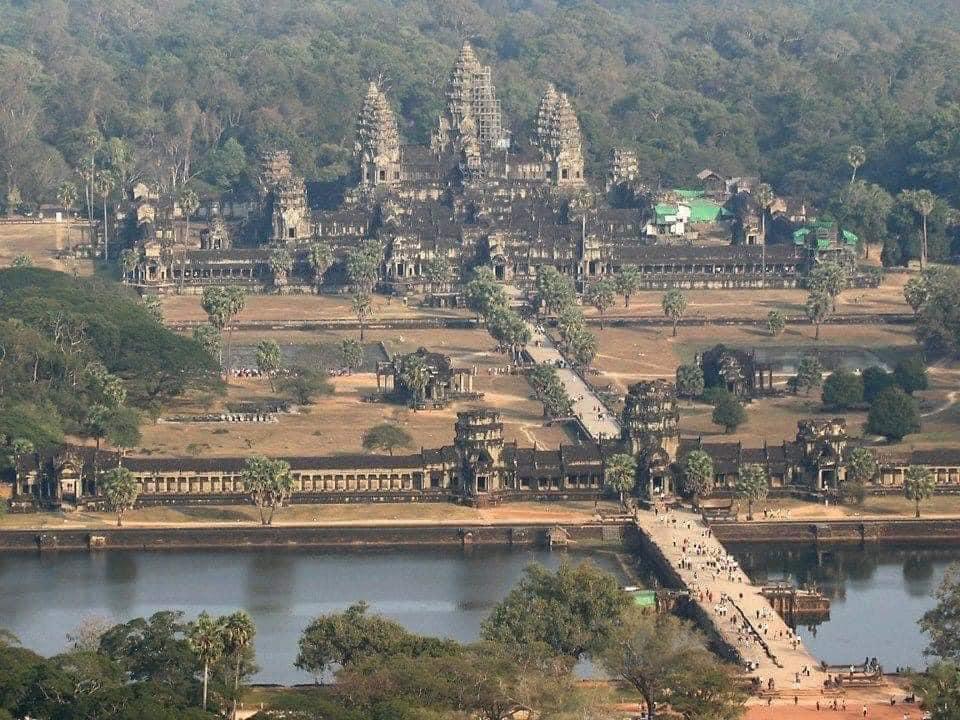 An aerial view of a temple with Angkor Wat in the background

Description automatically generated