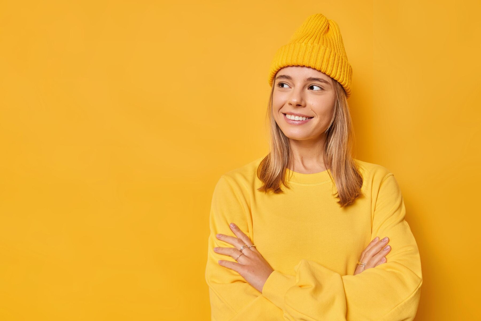 A woman wearing yellow looks away and smiles.