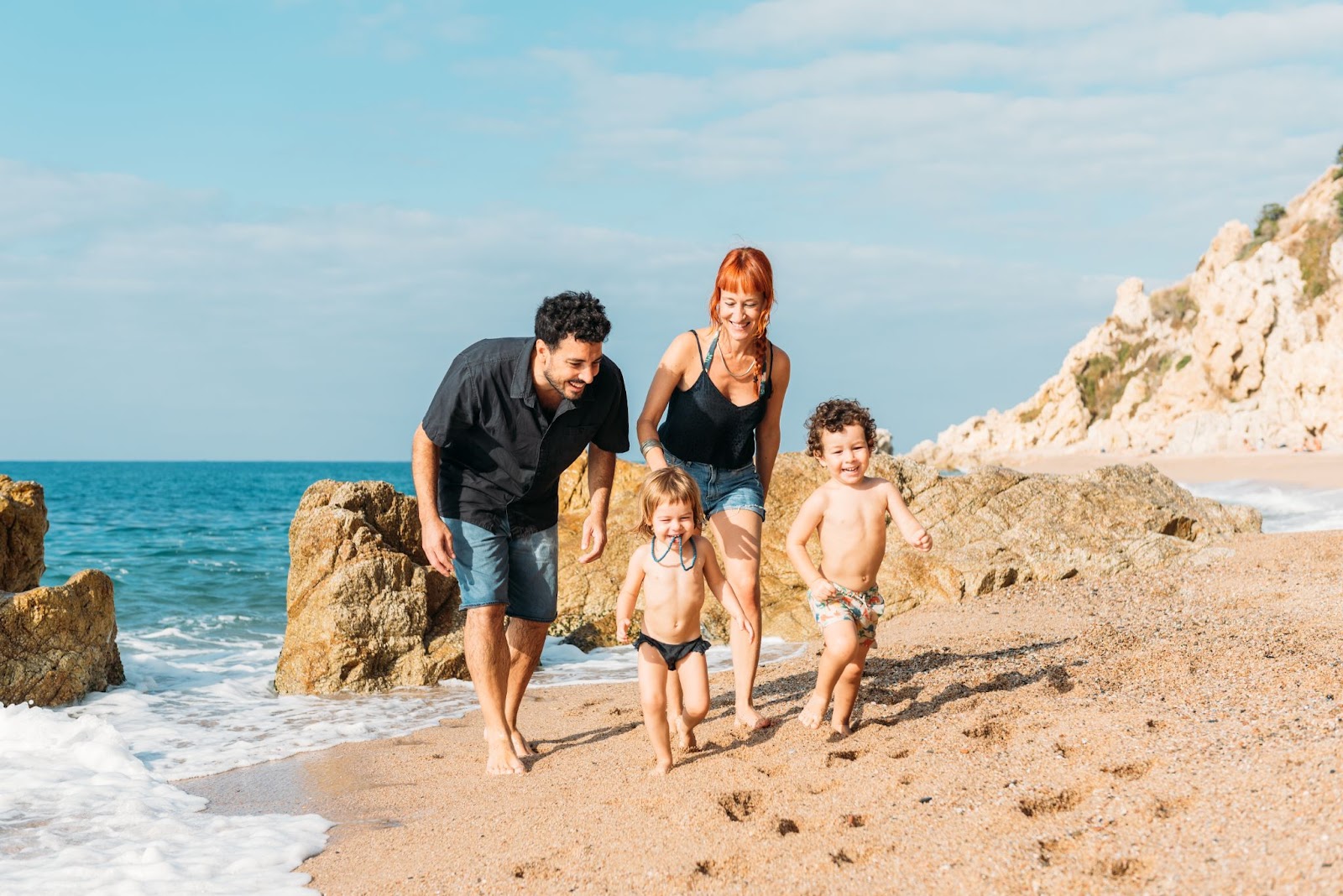A happy family walking on a sandy beach.