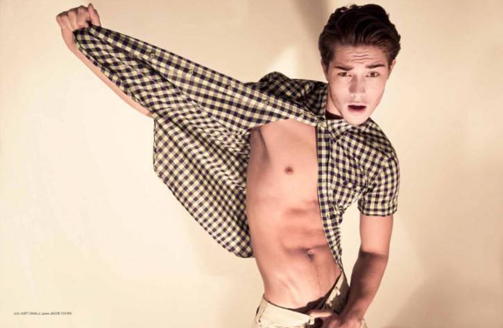 francisco lachowski wearing plaid button shirt unbuttoned to reveal his abs and torso while he looks shocked towards the camera in fashion gay photoshoot