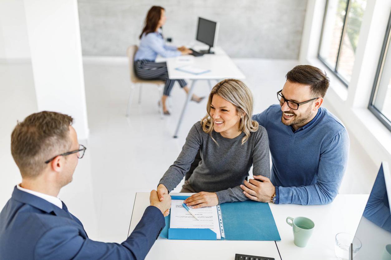 High angle view of a couple shaking hands with their insurance agent in the office.