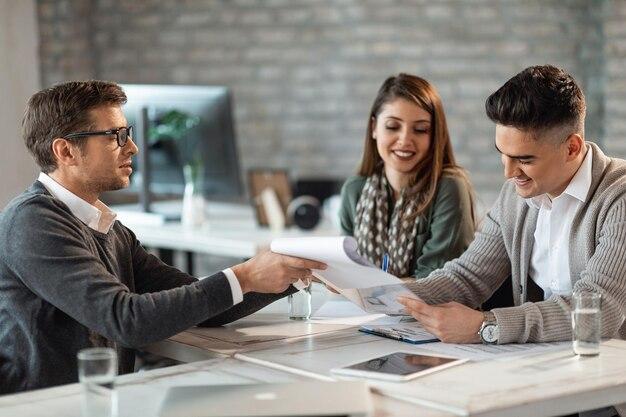 Free photo happy couple signing a contract on a meeting with their real estate agent in the office