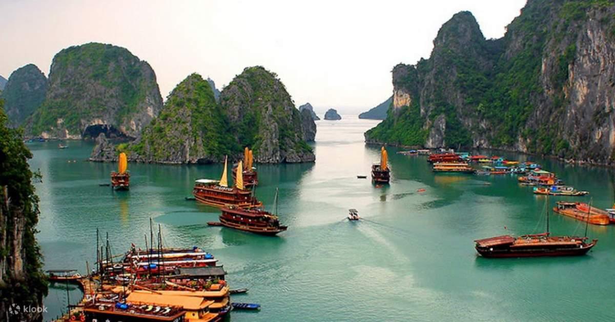 Boats in the water with mountains in the background with Ha Long Bay in the background

Description automatically generated