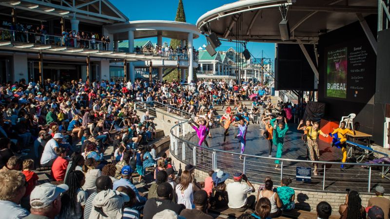 A lively free concert at the amphitheater of the Victoria & Alfred Waterfront in Cape Town, with a large crowd enjoying the performance.