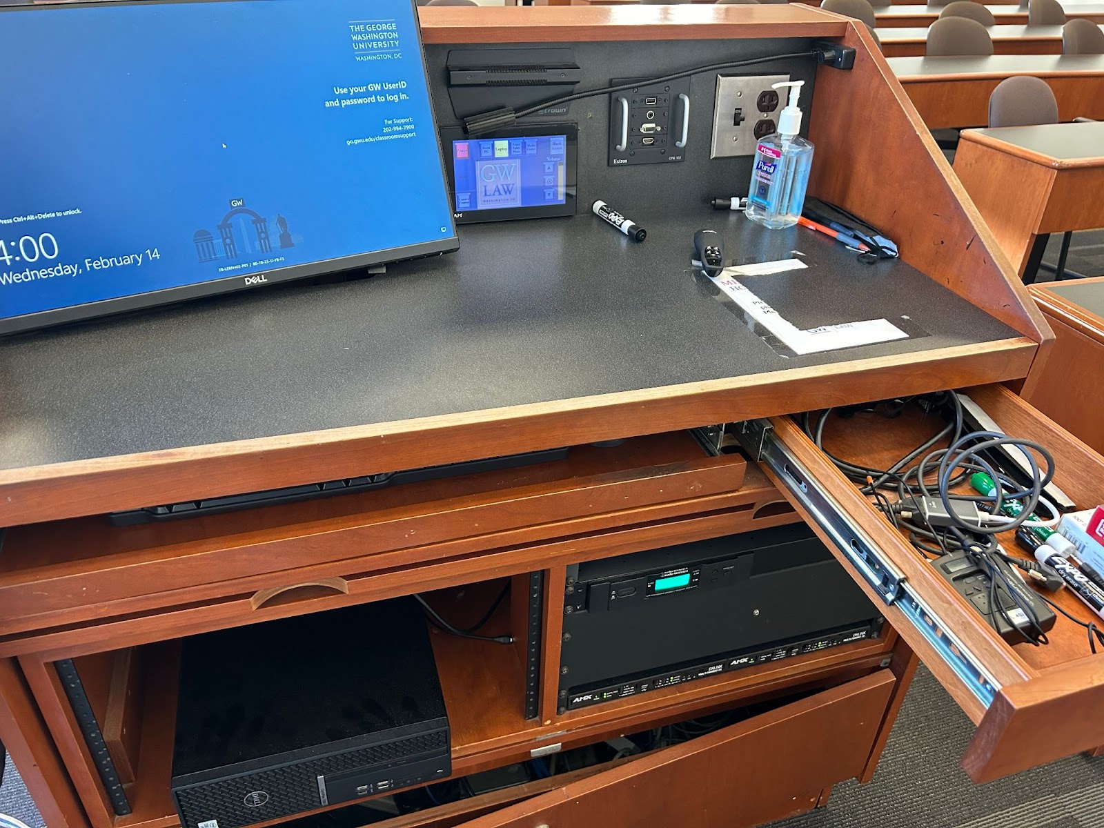 View of the lectern: computer and monitor, touch control panel, lapel mic in drawer.