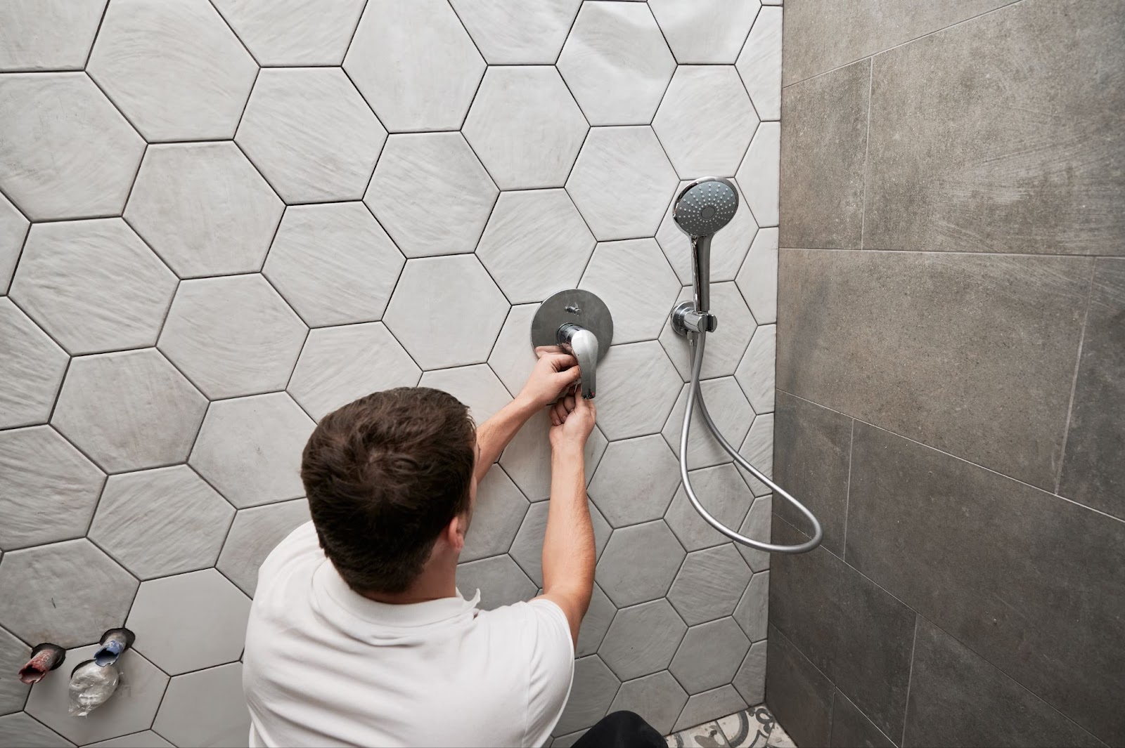 A man is installing a shower system in the bathroom.