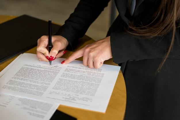 Free photo brunette businesswoman writing on a document