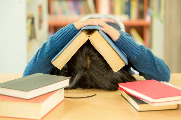 A student immersed in last-minute cramming, surrounded by open books in a college library. 