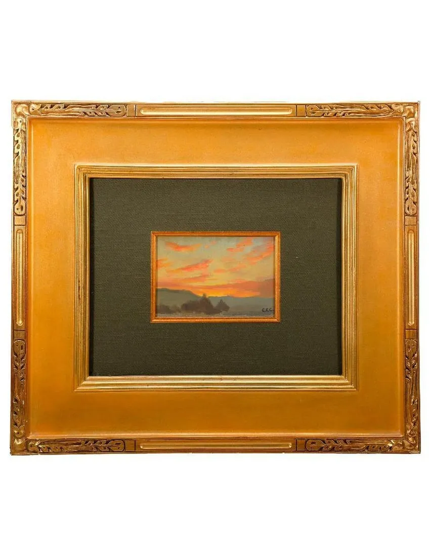 A gold framed picture of a sunsetDescription automatically generated
