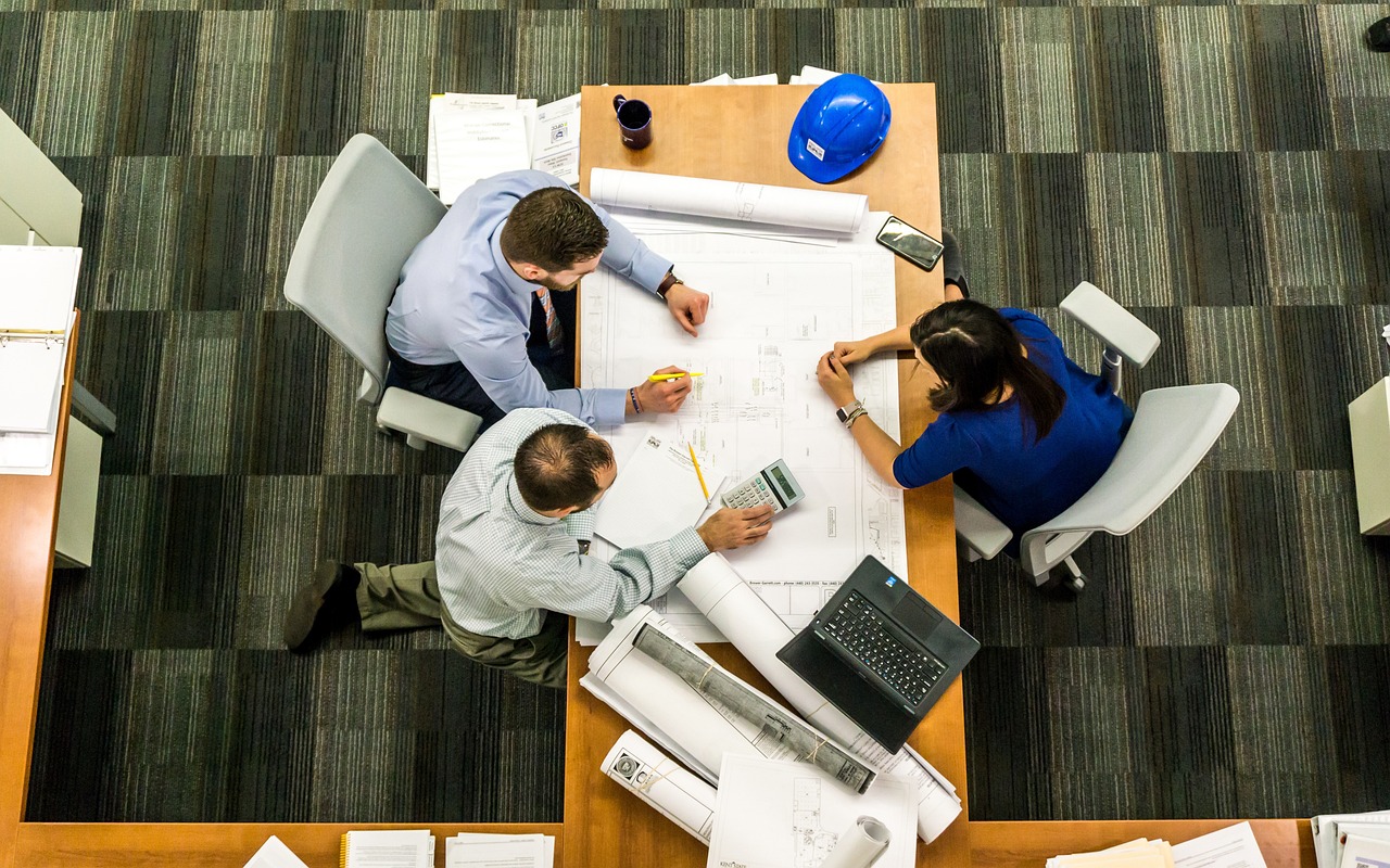 Birds-eye view of two men and one woman in business wear around a table covered in papers