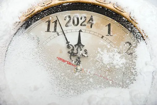 A snow-covered clock about to midnight but the "12" is "2024"